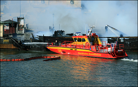 Brandbåten Fenix släcker från sjösidan.